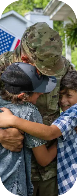 Military member hugging family.