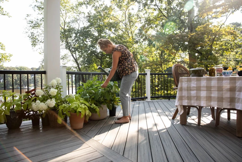 Woman tending to plants on a deck using Trex.
