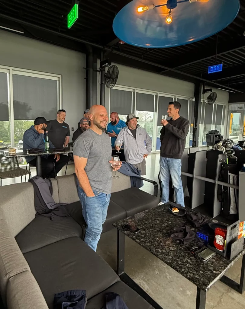 Photo of NexGen team members enjoying drinks and socializing at Top Golf.