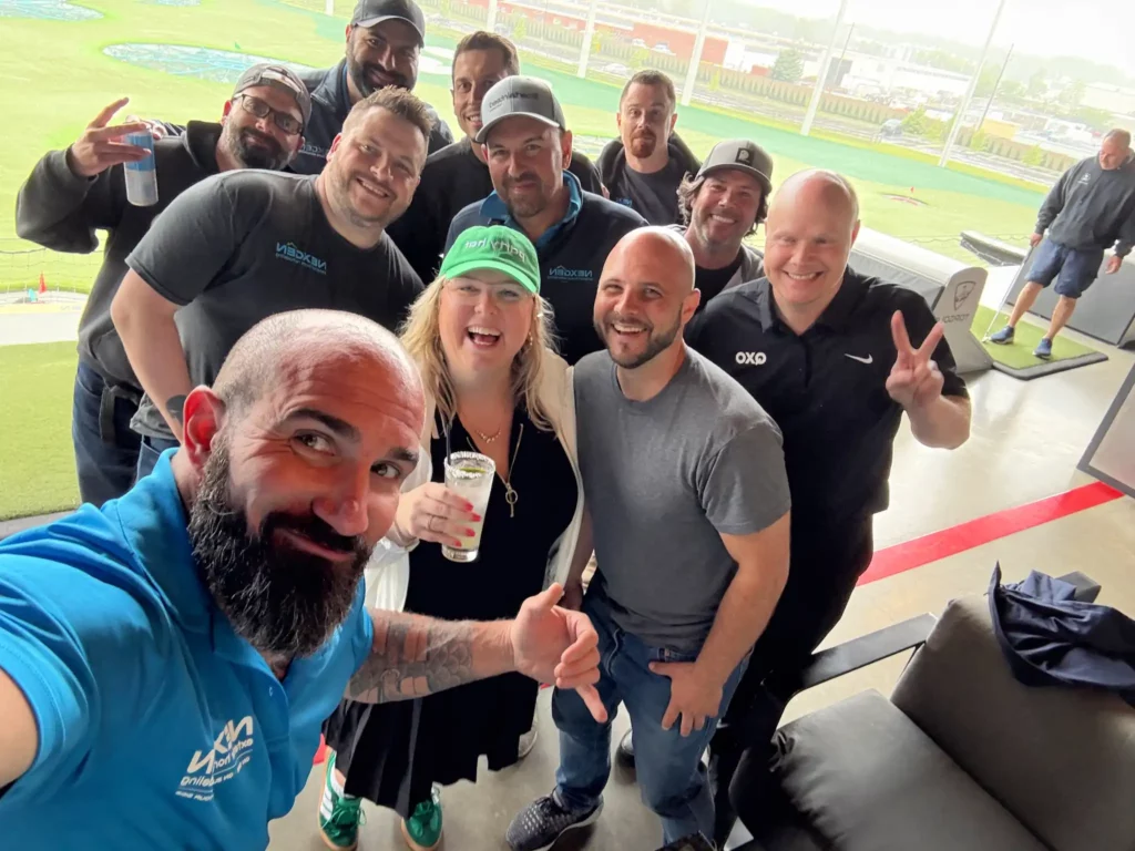 Group selfie of NexGen team members enjoying a day at Top Golf.
