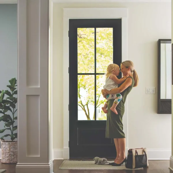 Photo of a mother holding her daughter while they laugh and look in into each other's eyes in front of their door.