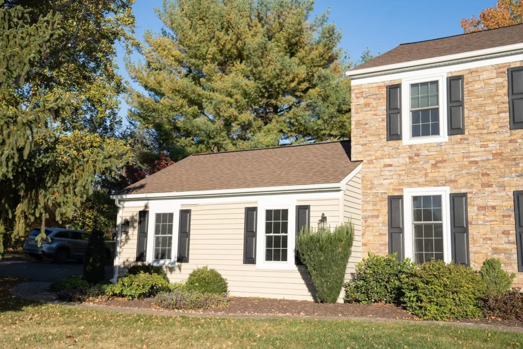 Photo of brick house with attached garage and brown & tan roof shingles.