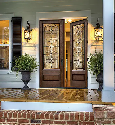 Photo of a dark wooden double front door with intricate patterned stain glass windows by ThermaTru.