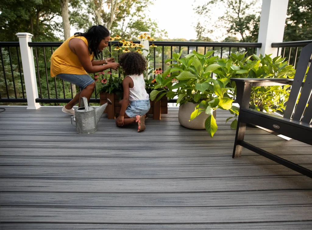 Photo of mother and child tending to flowers in a planter on a Trex Eco-friendly deck.