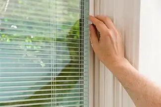 Close-up of window with integrated blinds being opened.