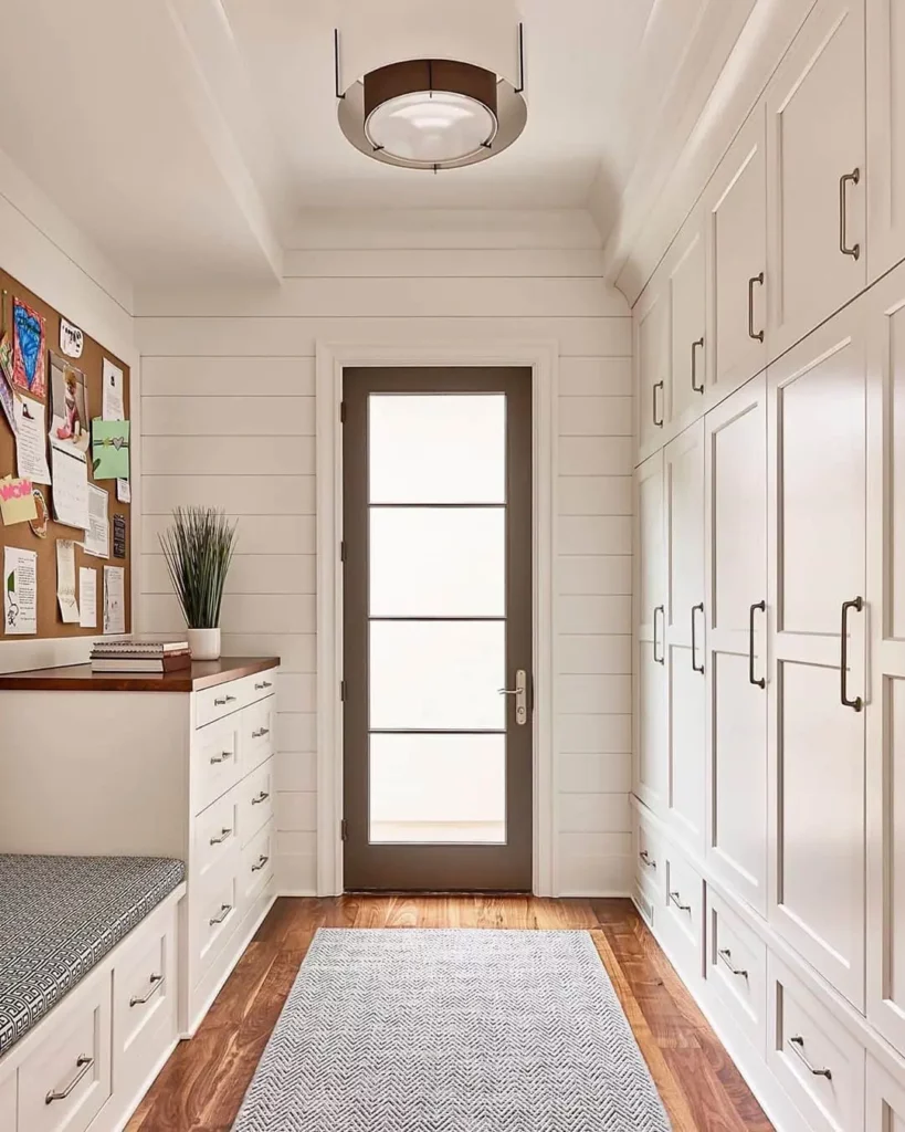 Photo of an entrance way with lots of cabinets and storage along either side leading to a wood-frame door with four vertical sections of glass representing the range of materials available from Pella Glass.