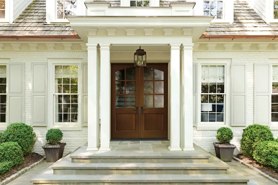 Photo of the a home with stone front porch and dark wood and glass door showing of the low maintenance need for ThermaTru Doors.