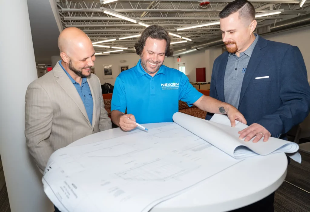 Photo of a NexGen remodeling team members meeting to discuss an architectural drawing.
