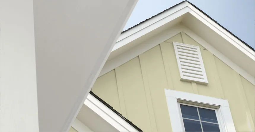 Photo of the peak of a home with beige/yellow James Hardie siding and white trim.