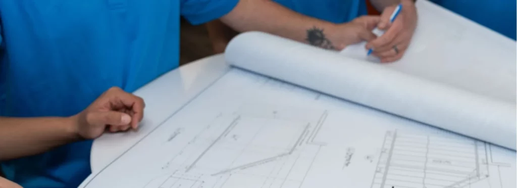 Close-up of an architectural drawing being reviewed by NexGen Remodeling team members.