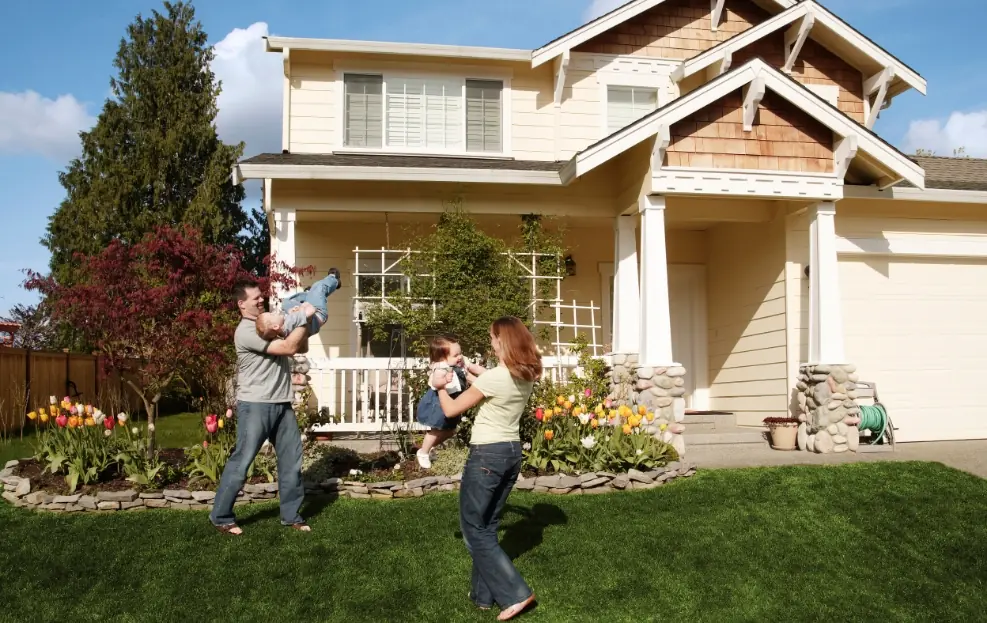 Photo of family with kids playing in front of their two-story home with professional landscaping.